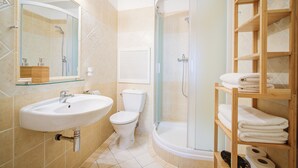 Une salle de bain équipée d’un lavabo, de toilettes, d’une douche et d’une étagère avec des serviettes.