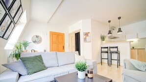 Un salon moderne comprenant un canapé, une table basse et un coin repas avec des chaises.
