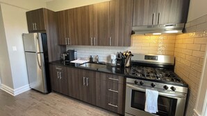 A modern kitchen with dark wood cabinets, stainless steel appliances, and a tiled backsplash.