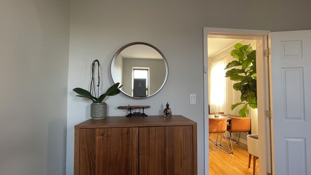 A wooden cabinet with a mirror and a potted plant.