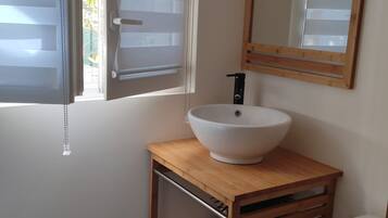 Een badkamer met een houten wastafelmeubel, een witte wasbak, een spiegel en een toilet.