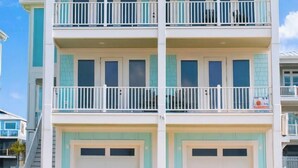 A multi-story building with balconies and garage doors. - BRAND NEW HOME, PRIVATE POOL, partial ocean view  By Williamson Realty (Ocean Isle Beach)