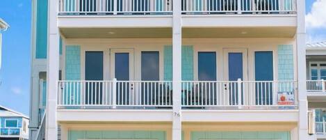 A multi-story building with balconies and garage doors.