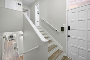 A staircase with white railings leading to a door with a black handle. - GP32A | G. Prairie Retreat | 3BD | Pool | 2 Patios (Grand Prairie)