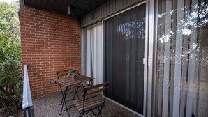 A patio with a table and chairs, a potted plant, and a sliding glass door.