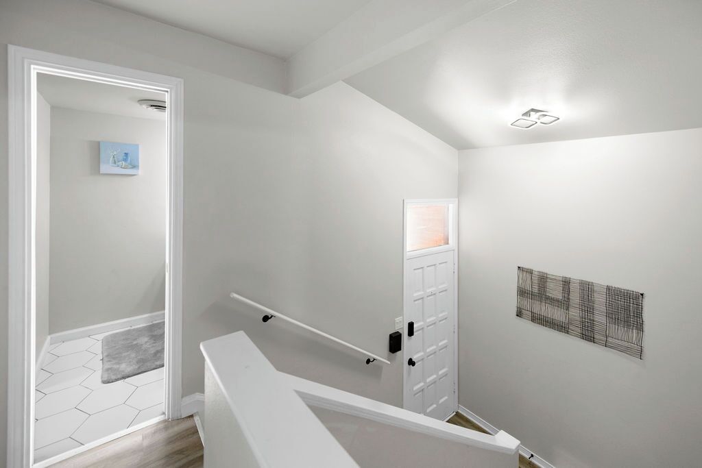 A modern interior with a staircase, a door with a small window, and a wall-mounted artwork.