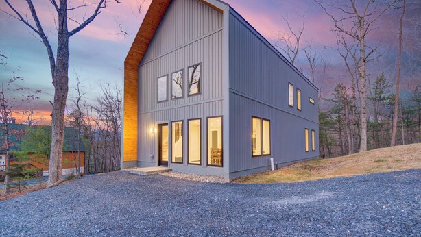 A modern two-story house with a sloped roof, large windows, and a gravel driveway. - Family Getaway 1 min to Bryce Resort! KING Bed! Fire Pit (Mount Jackson)
