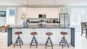 A modern kitchen with a central island, bar stools, pendant lighting, and a view of the outdoors. - Family Getaway 1 min to Bryce Resort! KING Bed! Fire Pit (Mount Jackson)