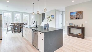 A modern kitchen with a large island, pendant lights, and a dining area with wooden chairs and a table. - Family Getaway 1 min to Bryce Resort! KING Bed! Fire Pit (Mount Jackson)