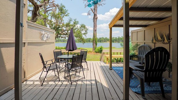 Una terraza de madera con una mesa y sillas, con vista a un lago.