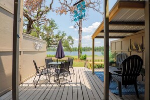 A wooden deck with a table and chairs, overlooking a lake. - Seas The Day with this cozy 2-bedroom lakefront condo. (Lake Park)