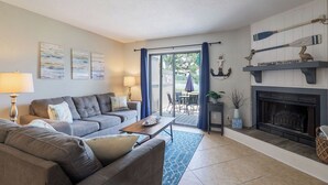 Una sala de estar con un conjunto de sofás, una chimenea y vistas al exterior.