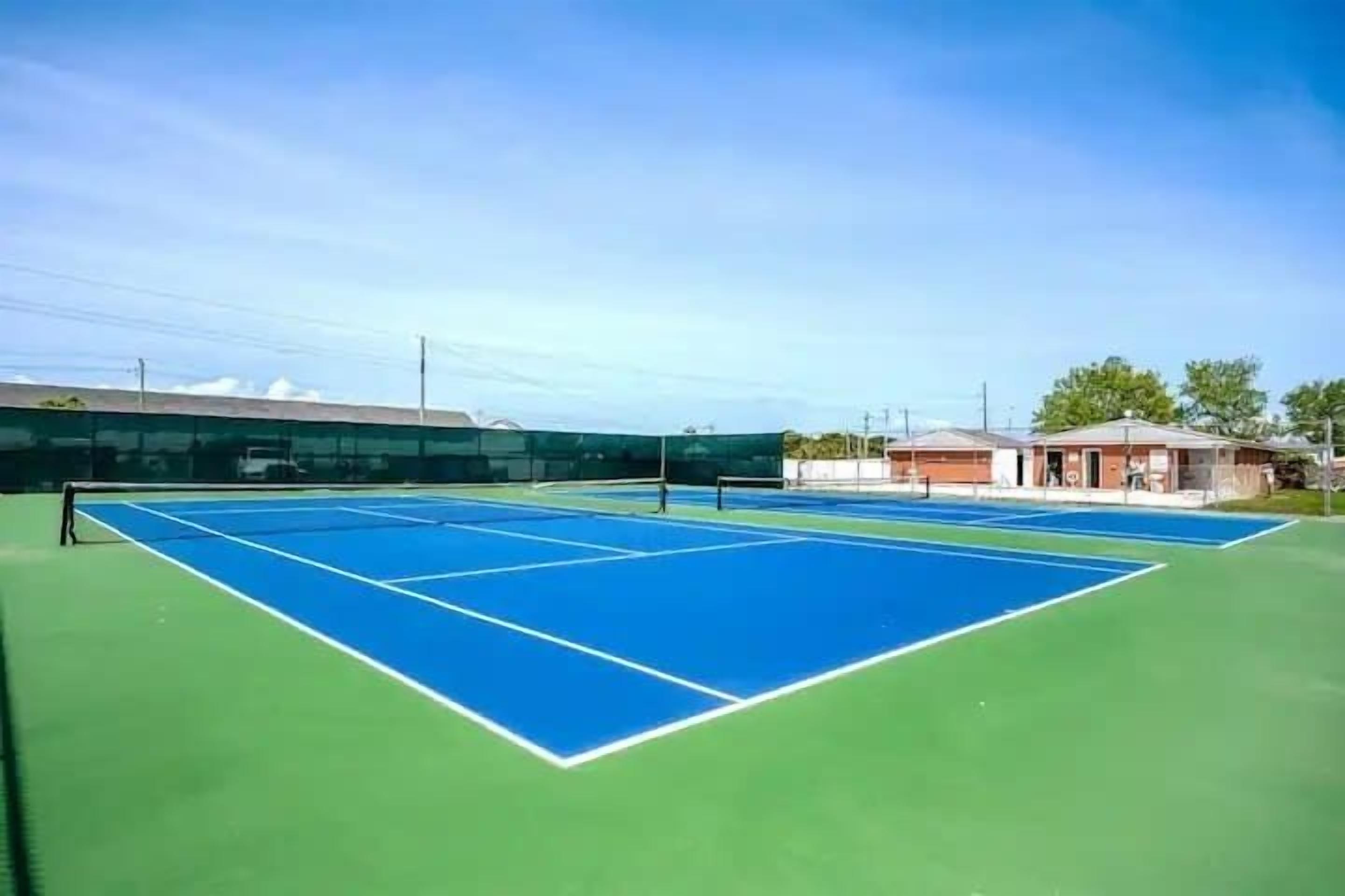 Ein Tennisplatz mit Netz, umgeben von Gebäuden.