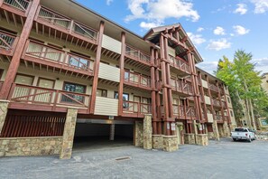 Un immeuble à plusieurs étages, doté de fondations en pierre, de balcons en bois et d’une entrée de garage.