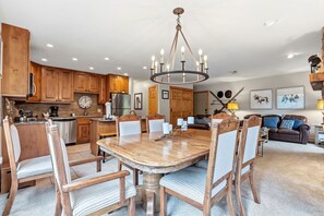 A spacious kitchen with wooden cabinets, a large dining table, and a chandelier.