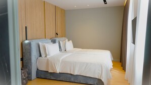A modern bedroom with a large bed, a wooden panel wall, and a minimalist design. - Arbnor Boutique Hotel (Tirana)