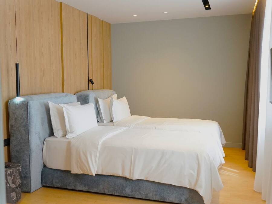 A modern bedroom with a large bed, a wooden panel wall, and a minimalist design.