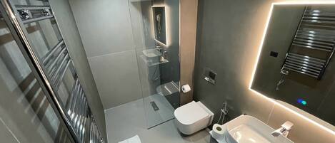 Ein modernes Badezimmer mit Duschkabine aus Glas, Toilette und Waschbecken mit Spiegel.