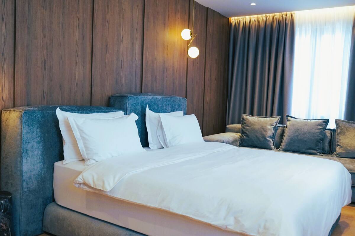 Une chambre d’hôtel moderne avec un grand lit, un canapé et un mur décoratif en bois.