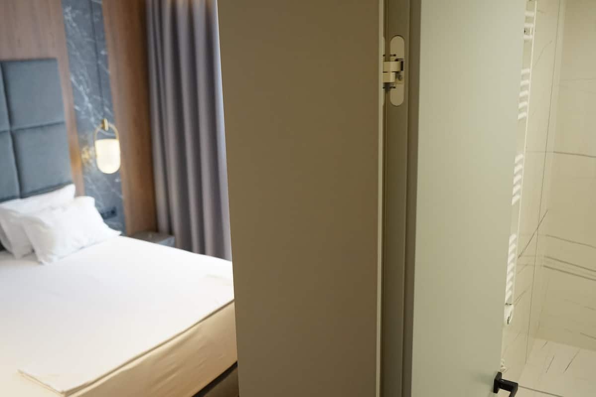 Une chambre d’hôtel avec un lit, une tête de lit et une porte.