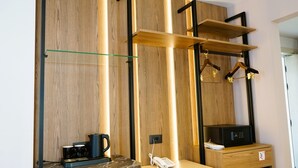 A modern hotel room with a wooden panel wall, a coffee maker, mugs, a telephone, and a microwave. - Arbnor Boutique Hotel (Tirana)