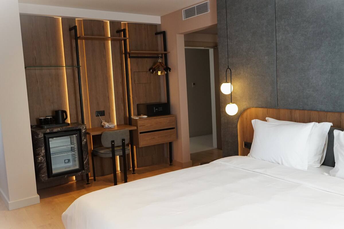 Une chambre d’hôtel équipée d’un lit, d’un bureau avec un ordinateur, d’une chaise et d’un mini-bar.