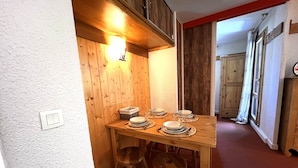 A wooden dining table with plates and glasses, a light switch, and a wooden stool.