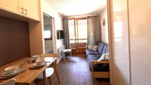 A compact room with a dining table, a sofa, and a television. - Skis on your feet (La Plagne Tarentaise)