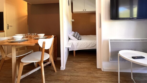 A compact hotel room with a dining area, a bed, and a TV. - Skis on your feet (La Plagne Tarentaise)