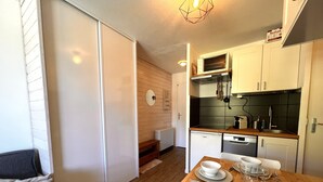 A compact kitchen with wooden cabinets, a microwave, and a dishwasher. - Skis on your feet (La Plagne Tarentaise)