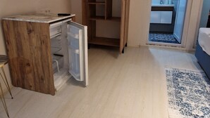 Huoneessa on puinen vaatekaappi, pieni työpöytä, televisio ja kylpyhuone, joka näkyy avoimesta ovesta.