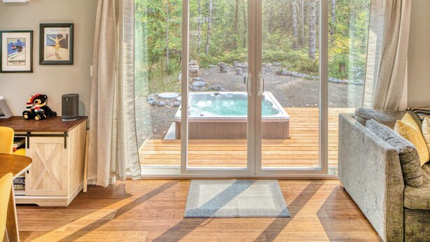 A cozy living room with a sliding glass door leading to a deck with a hot tub. - A-Frame of Mind - Secluded Escape  Hot tub (Rhododendron)