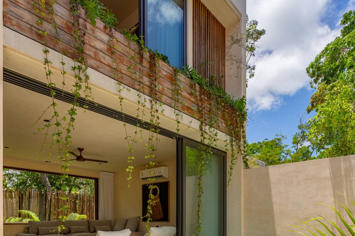 A modern house with a swimming pool, a balcony with plants, and a living room with a sofa and coffee table.