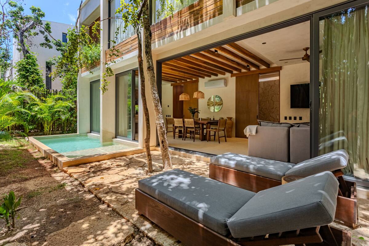 A modern house with a pool, outdoor seating, and a dining area.