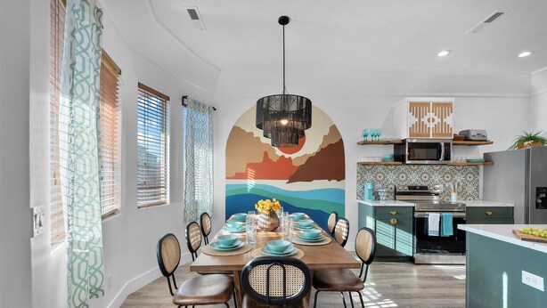 Une cuisine moderne dotée d’un îlot central, d’appareils électroménagers intégrés et d’un coin repas avec une grande table pouvant accueillir six personnes.