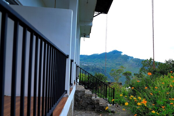 A staircase with a black railing leading to a white building with a stone base. - O2 Haputale (Haputale)