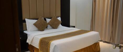A neatly made bed with a headboard, white bedding, and two decorative pillows.
