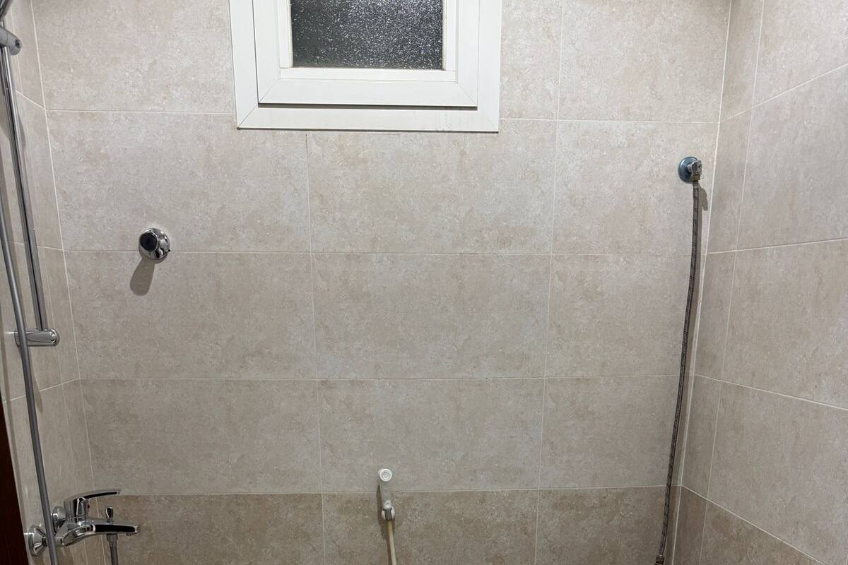 Pieni, laatoitettu kylpyhuone, jossa on wc, bidee ja suihku.