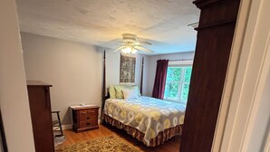 A bedroom with a bed, a ceiling fan, a nightstand, a rug, and a window with curtains. - Private, beautiful and quiet bedroom with private bathroom in county farmhouse.  (Norfolk)