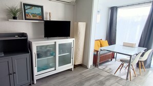 Ein kompakter Wohnraum mit Küchenzeile, Essbereich und Fernseher.