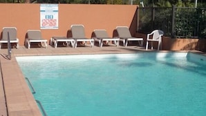 Ein Schwimmbecken mit Liegestühlen und einem Schild an der Wand.