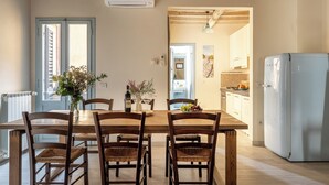 A dining area with a wooden table and chairs, a vase with flowers, and a refrigerator. - San Cristofano Blu Apartment Florence (Florence)