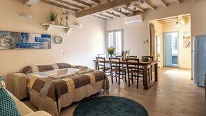 A cozy living room with a sofa, a dining table with chairs, and a kitchen area visible through an open door. - San Cristofano Blu Apartment Florence (Florence)