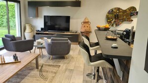 Un salon moderne avec un téléviseur, des sièges et un coin repas.