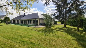 Une maison dotée d’une grande pelouse, d’un patio couvert et d’un jardin bien entretenu.