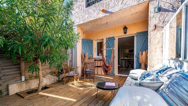 A wooden deck with outdoor furniture, a hammock, and a large tree.