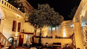 Une cour extérieure avec des murs en pierre, un arbre et des sièges pour se détendre en plein air.