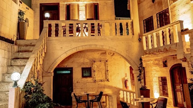 Une cour avec un escalier en pierre, des sièges extérieurs et un balcon en bois.