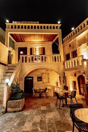 A courtyard with a stone staircase, outdoor seating, and a wooden balcony. - Sermest House (Sanliurfa)