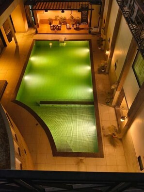 An indoor swimming pool with a green water feature, surrounded by a tiled area with seating and plants. - Rani Palace Hotel And Resort  (Kishangarh)